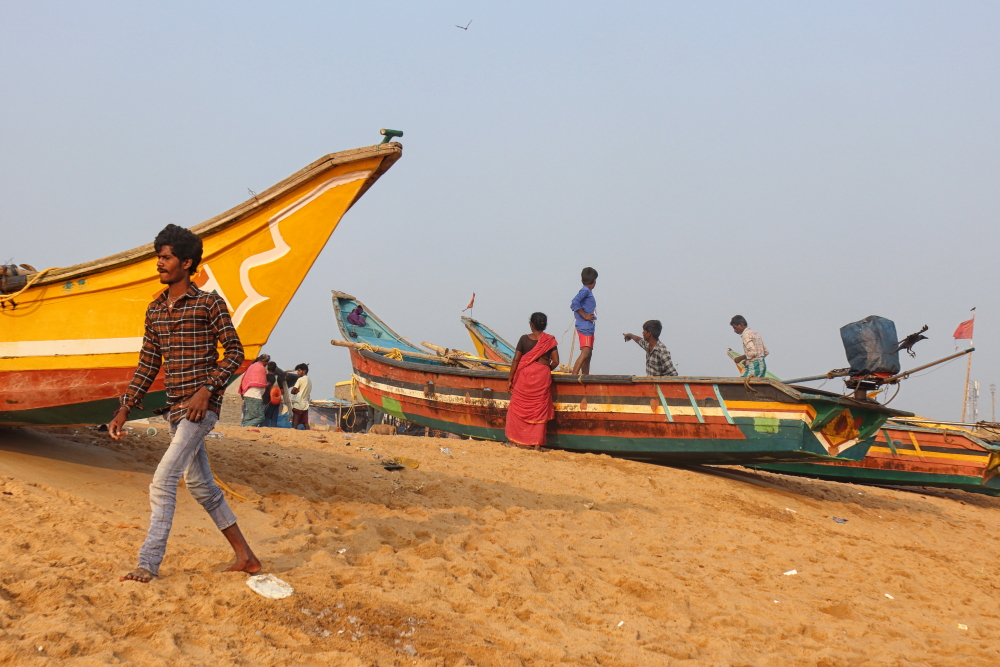 Children playing on anchored fishing boats in Penthakata sea beach
