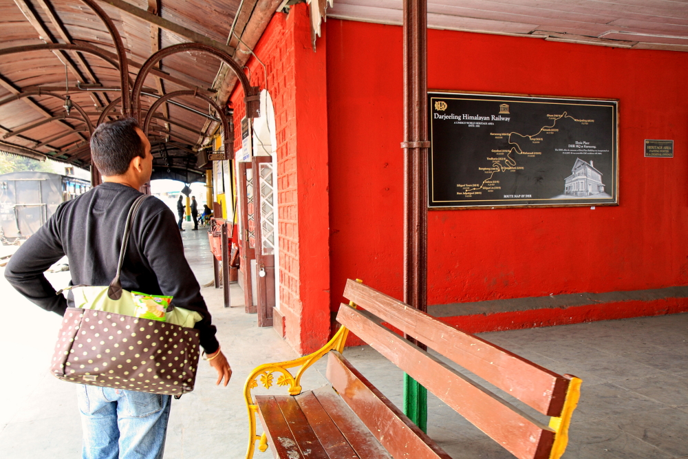 Image showing a tourist looking at a Darjeeling Himalayan Railway map in Ghum station.