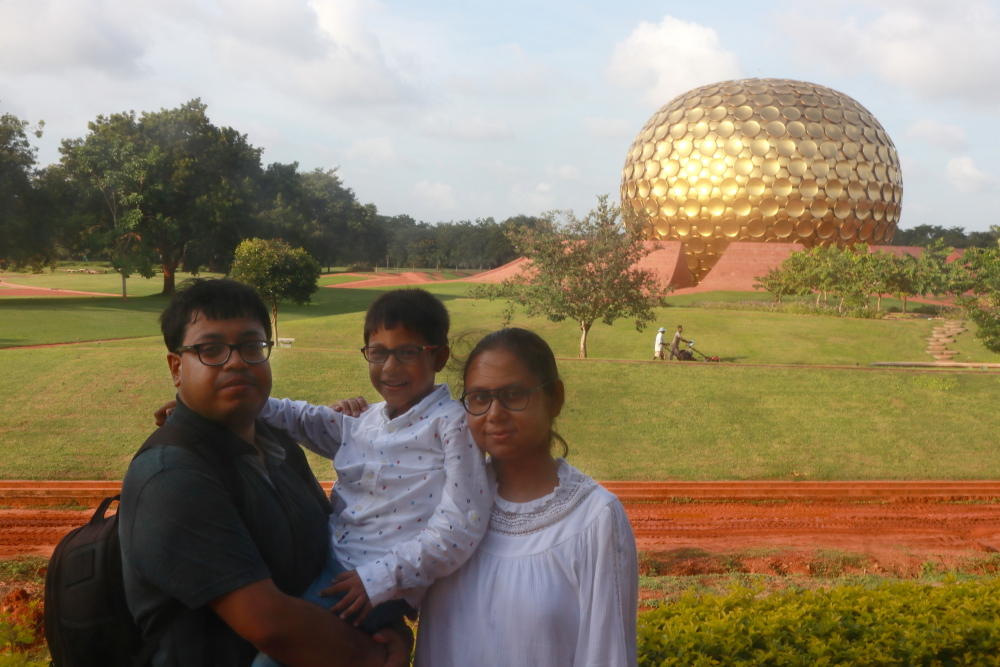 A family portrait at the Matrimandir ViewPoint with the golden dome behind.